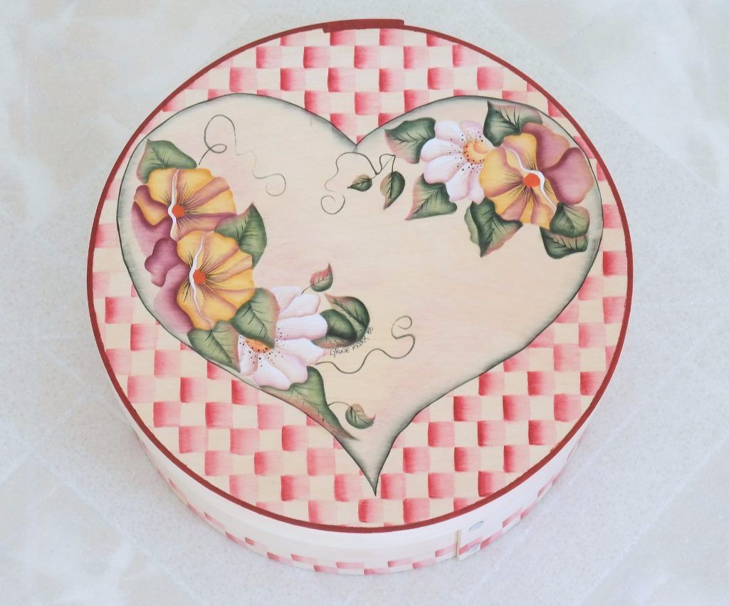 Round folk art box hand-painted with a floral heart on a pink check ground